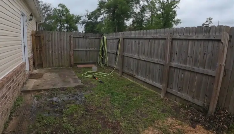 Fence line with uneven mildew weathering before cleaning